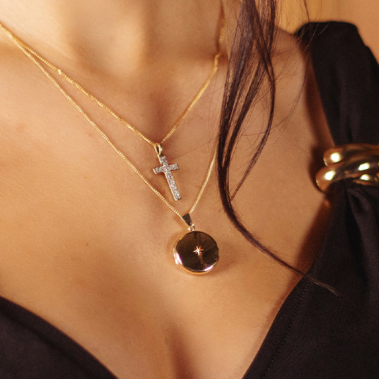 woman wearing a round shaped gold locket with a diamond at its centre on a gold chain