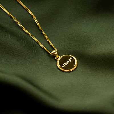 engraved necklace in gold on green satin fabric
