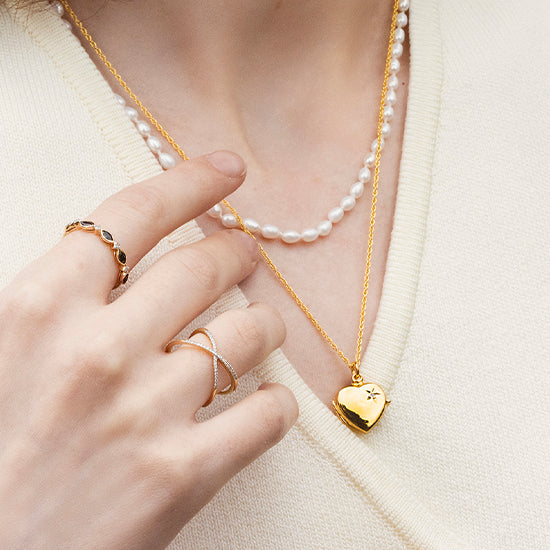 female model in a white shirt wearing a gold diamond locket