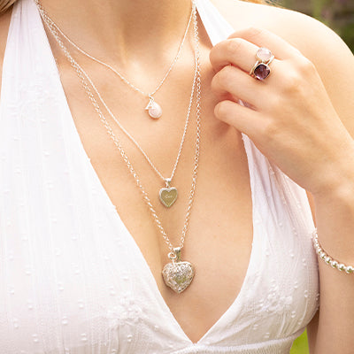 Female model in white low cut neckline dress wearing three Lily Blanche necklaces layered