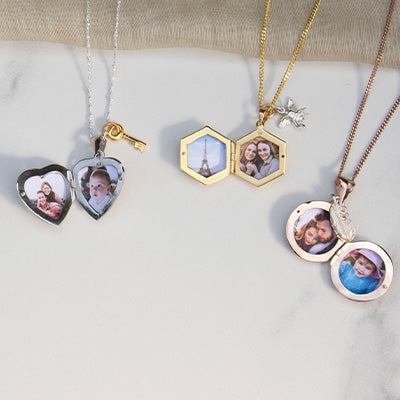 Three Lily Blanche lockets in different shapes lying open and displaying the photographs inside them