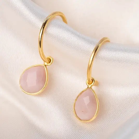 a tear shaped citrine gemstone necklace in gold on a gold chain against a piece of beige fabric