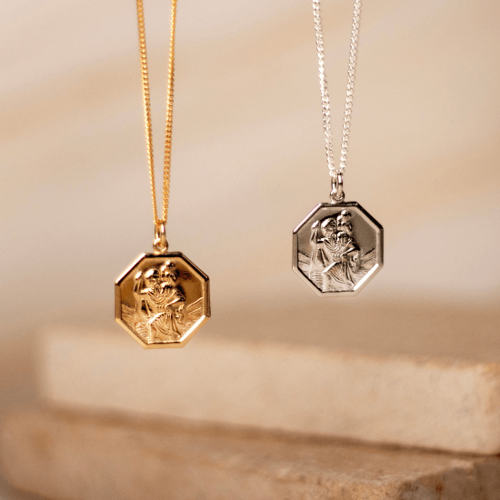 Gold vermeil and sterling silver St Christopher necklaces with octagonal pendants, displayed on a neutral stone background.