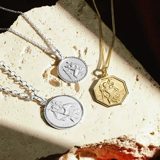 man holding a gold st Christopher necklace on a gold chain close up angle