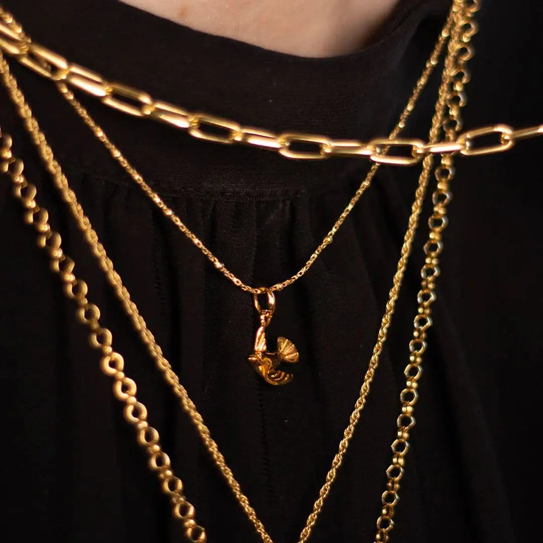 Layered gold chains with bird charm pendant, elegant statement layering jewellery look