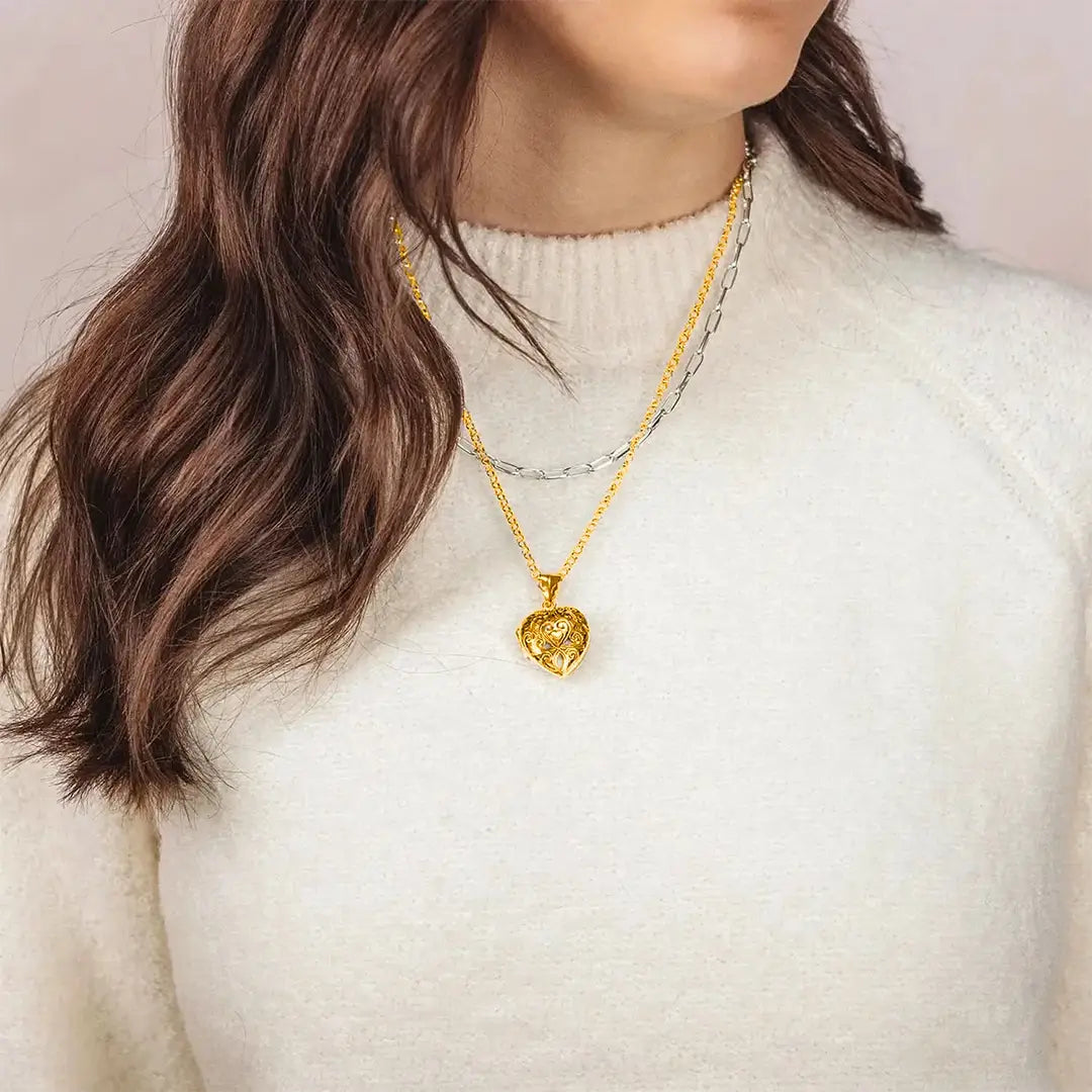 Woman wearing gold filigree heart locket necklace layered with silver chain