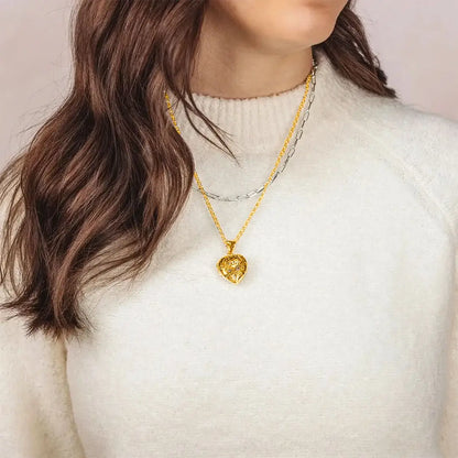 Woman wearing gold filigree heart locket necklace layered with silver chain