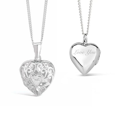 Front and back views of a sterling silver filigree heart locket necklace. The front features an intricate openwork scroll design with a small heart at the centre, while the back is polished and engraved with the words "Love You". The locket hangs from a sterling silver chain against a white background.