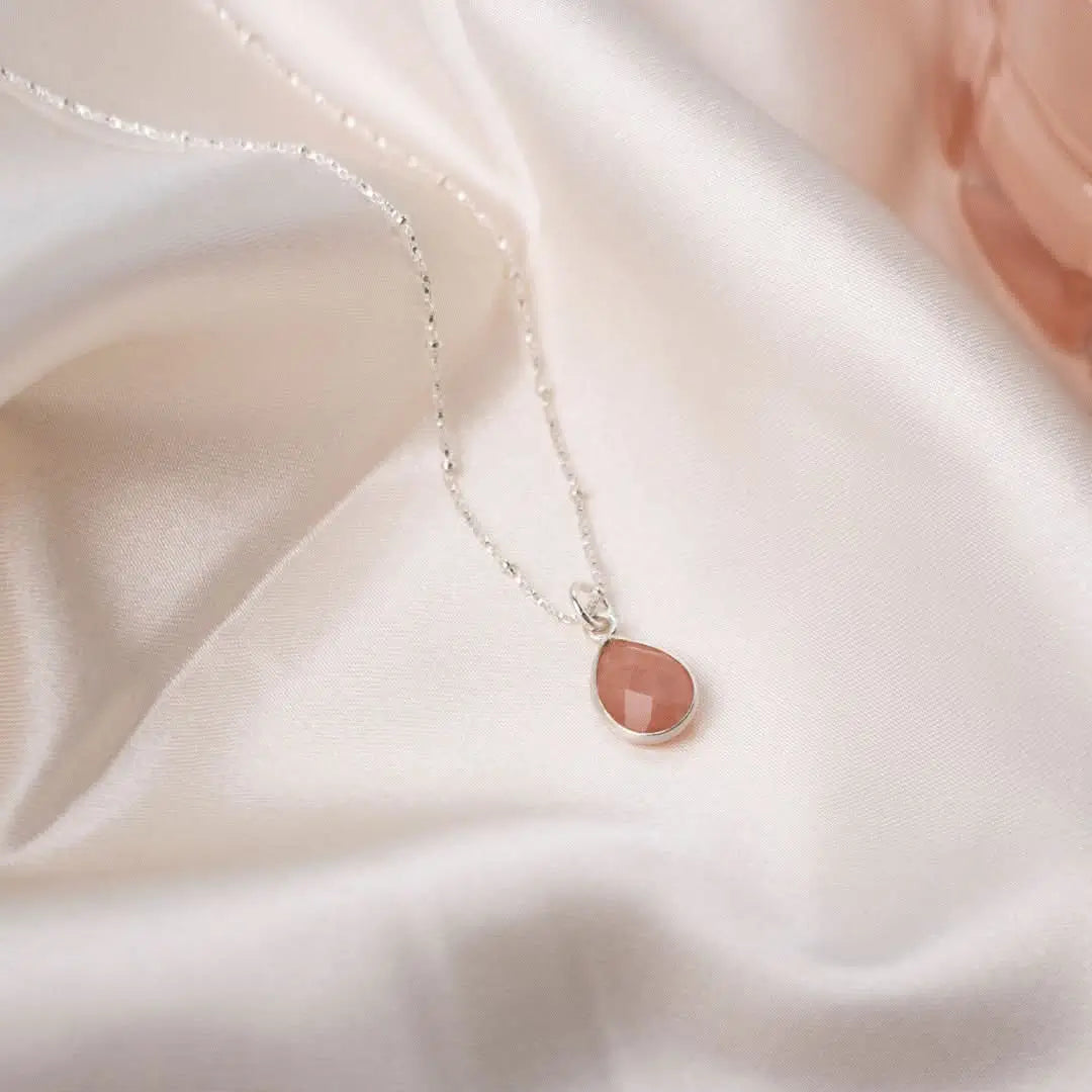 Pink opal teardrop necklace in sterling silver on soft silk background, delicate feminine gemstone jewellery