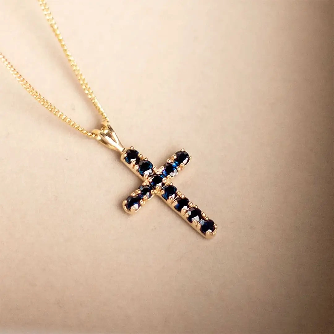 Gold sapphire cross necklace with deep blue gemstones on fine chain, delicate luxury pendant