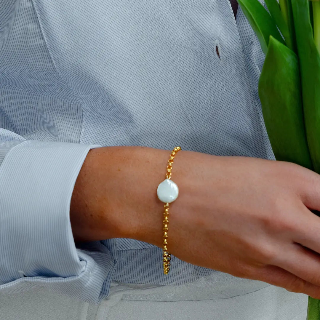 Woman wearing gold coin pearl bracelet with blue shirt, elegant freshwater pearl jewellery styling