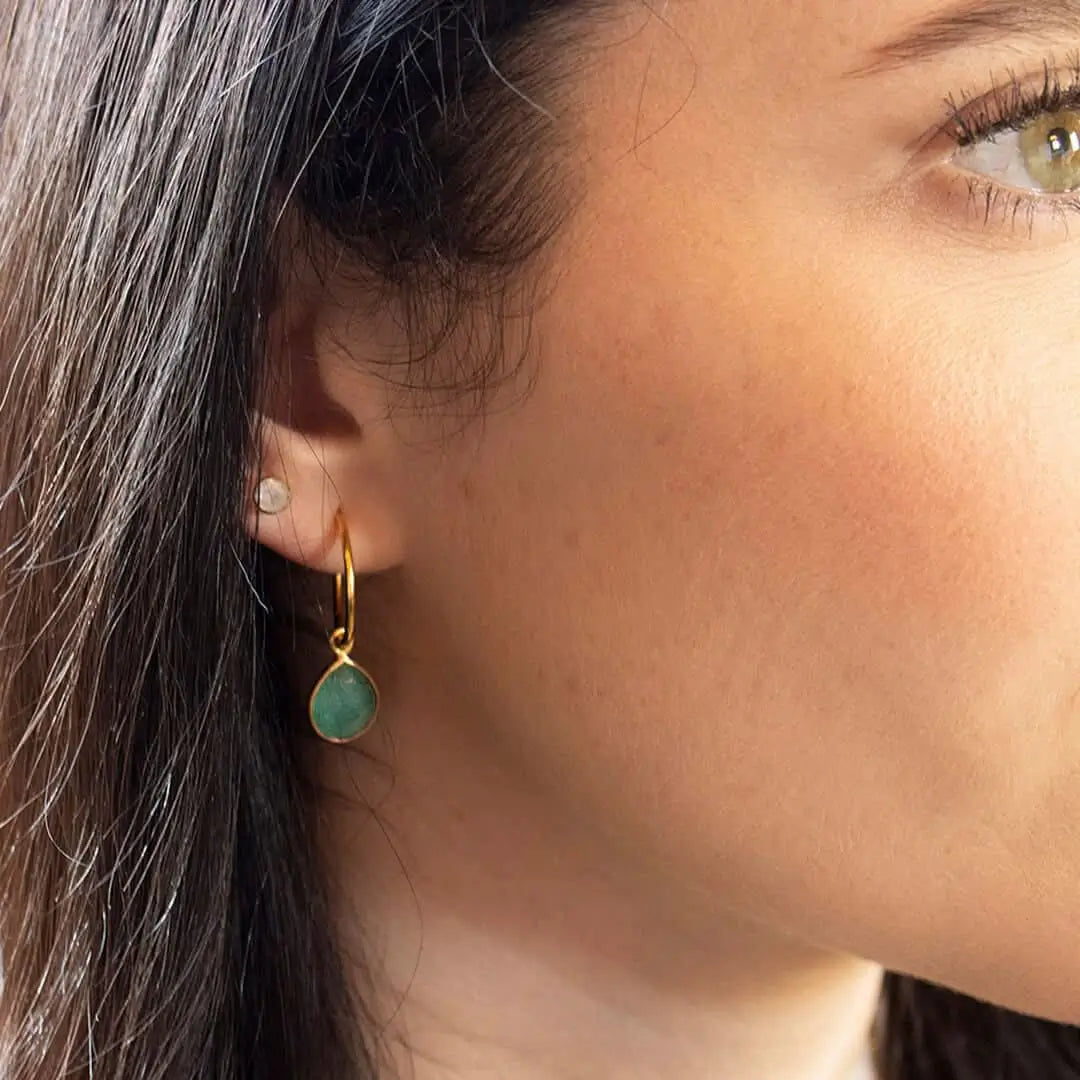 Woman wearing gold chrysoprase drop hoop earrings with green gemstone, elegant everyday styling