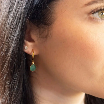 Woman wearing gold chrysoprase drop hoop earrings with green gemstone, elegant everyday styling