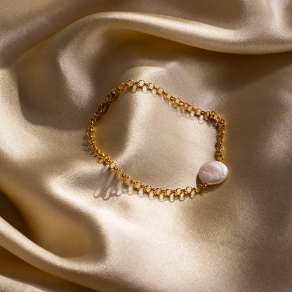 Gold coin pearl bracelet displayed on gold satin fabric, highlighting natural pearl lustre and texture