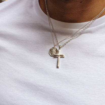 Sterling silver cross pendant necklace layered with St Christopher pendant on chains, worn by male model