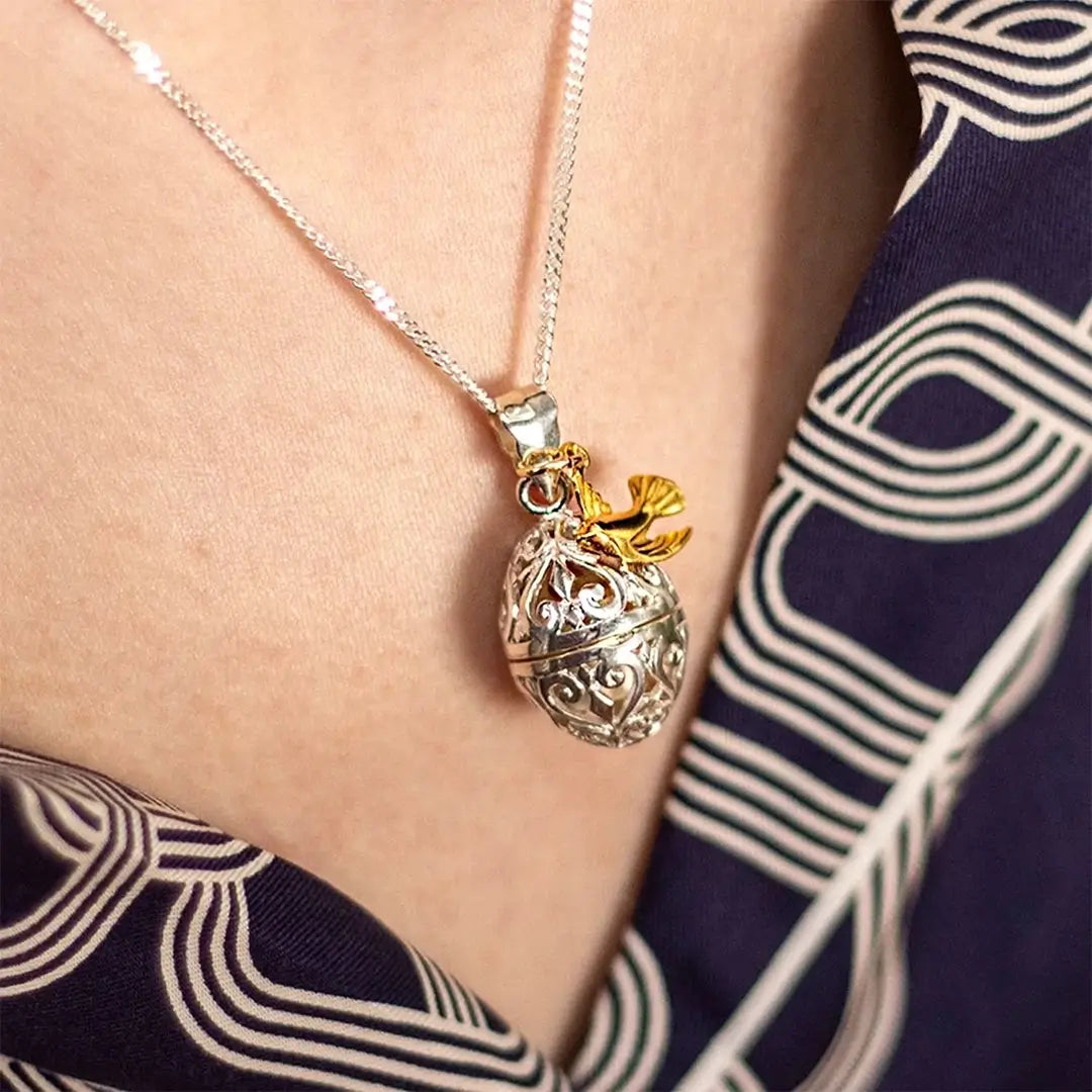 Sterling silver filigree locket with gold dove charm worn by model, elegant sentimental jewellery piece