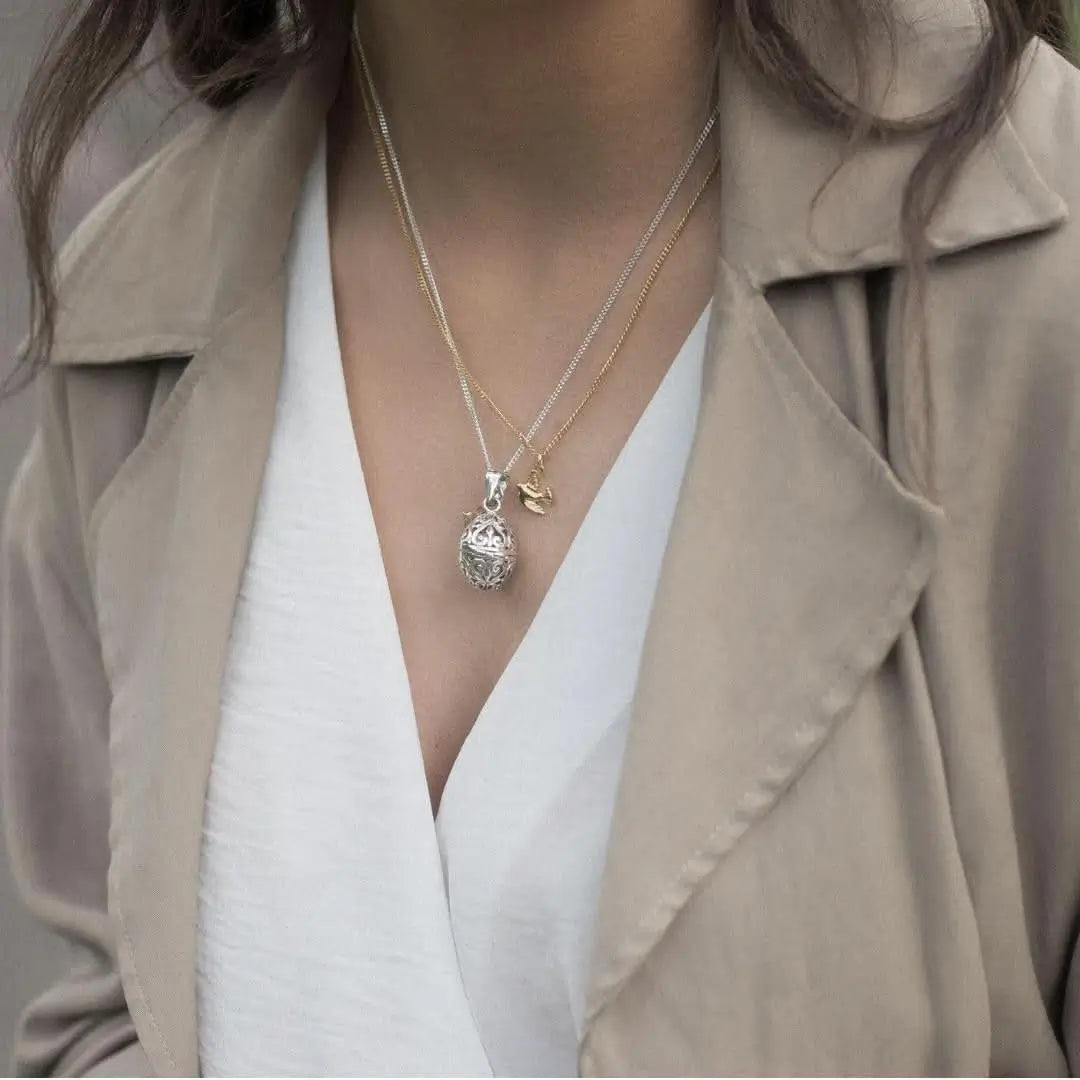 Layered necklaces featuring bird charm and filigree locket, meaningful personalised jewellery styling
