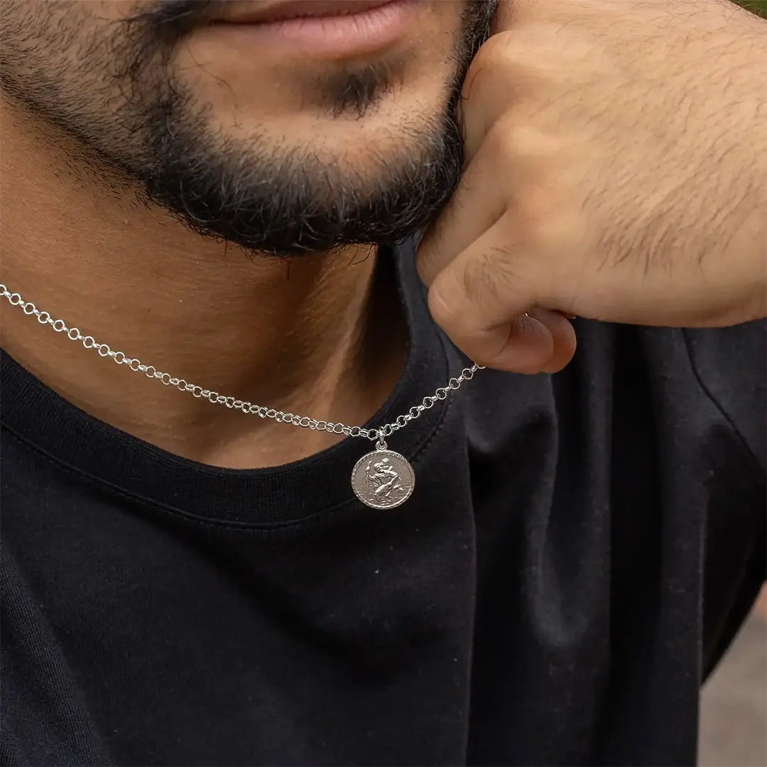 Sterling silver St Christopher necklace worn by man on black t-shirt, patron saint of travellers pendant close-up