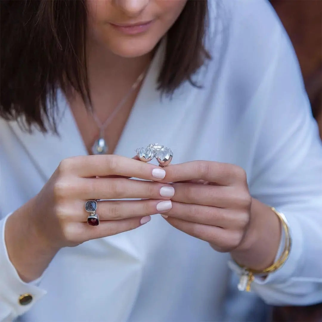 Close-up of model holding silver chick locket necklace, showing scale and polished egg pendant design
