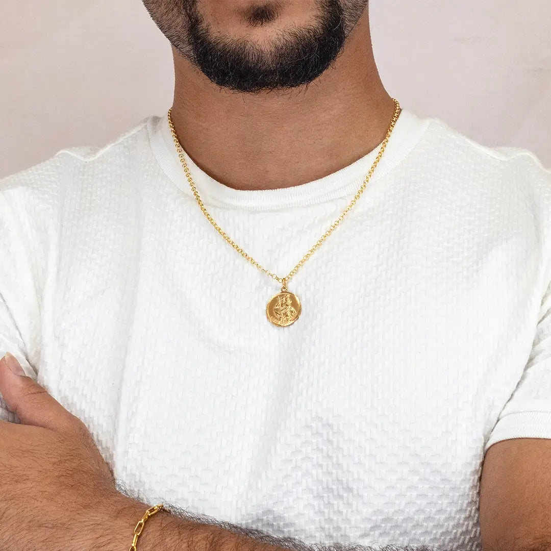 Men’s gold St Christopher coin necklace worn on fine chain with casual white outfit