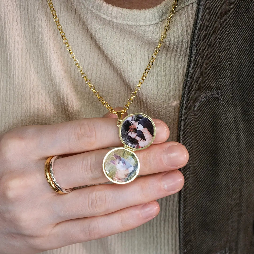 Close-up of a person holding an open gold St Christopher locket displaying two personalised photos inside