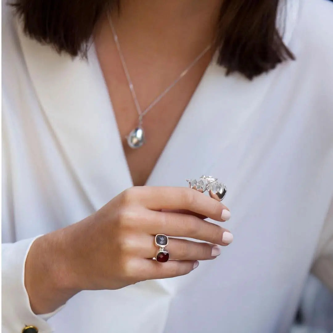 Close-up of opened sterling silver egg locket revealing small chick inside, held in hands for scale

