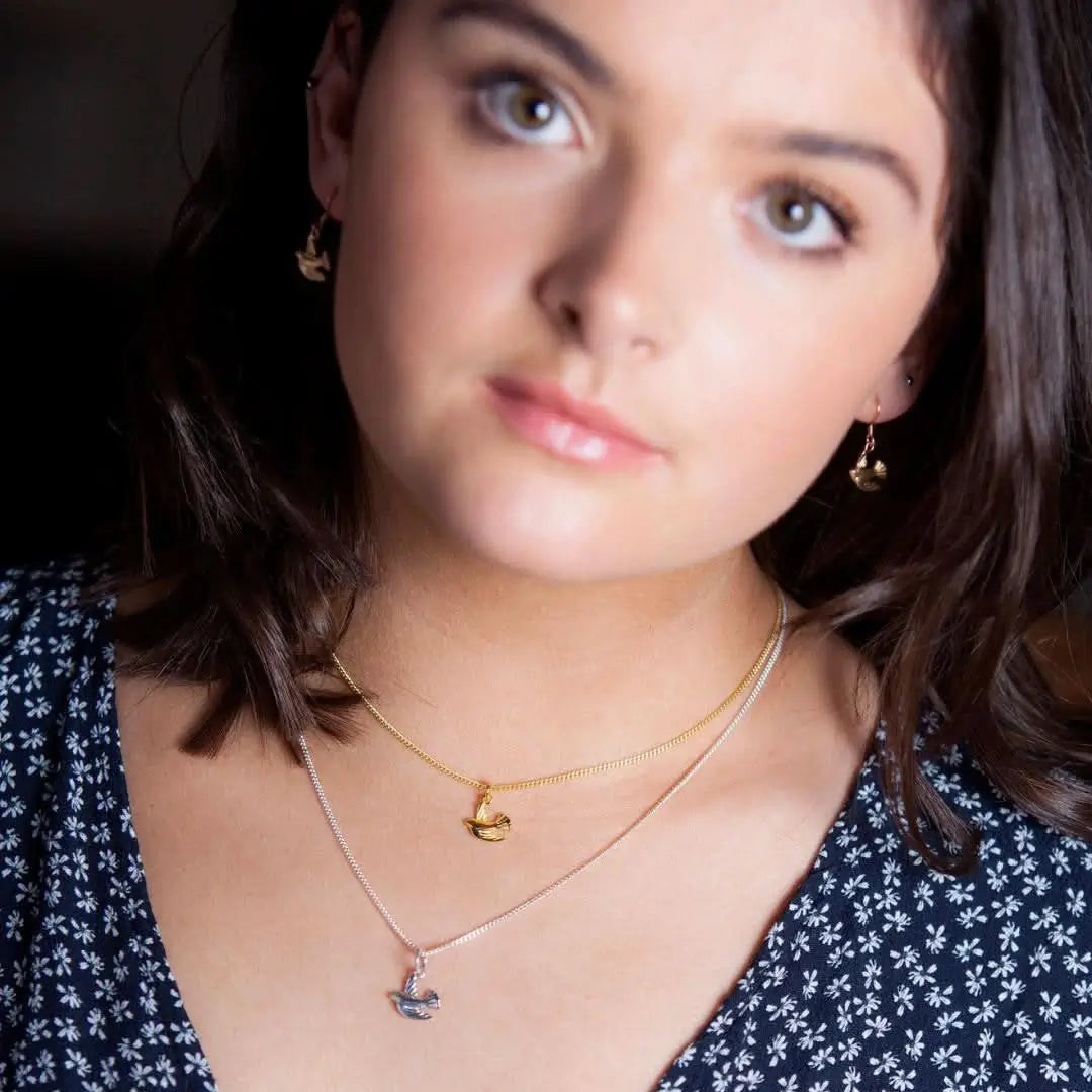 Gold bird charm necklace and earrings worn by model, elegant symbolic jewellery set
