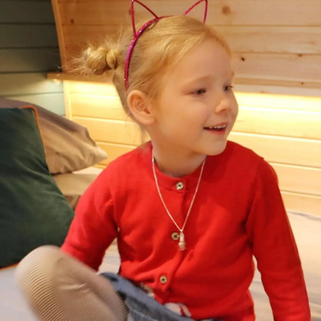 Child wearing sterling silver rabbit pendant necklace, cute bunny jewellery styled with red cardigan