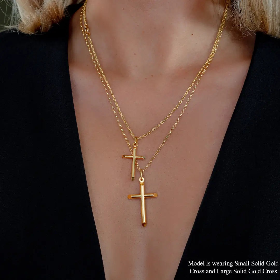 Model wearing layered solid  9ct gold cross pendant necklaces featuring small and large polished cross designs on fine chains, styled with black outfit