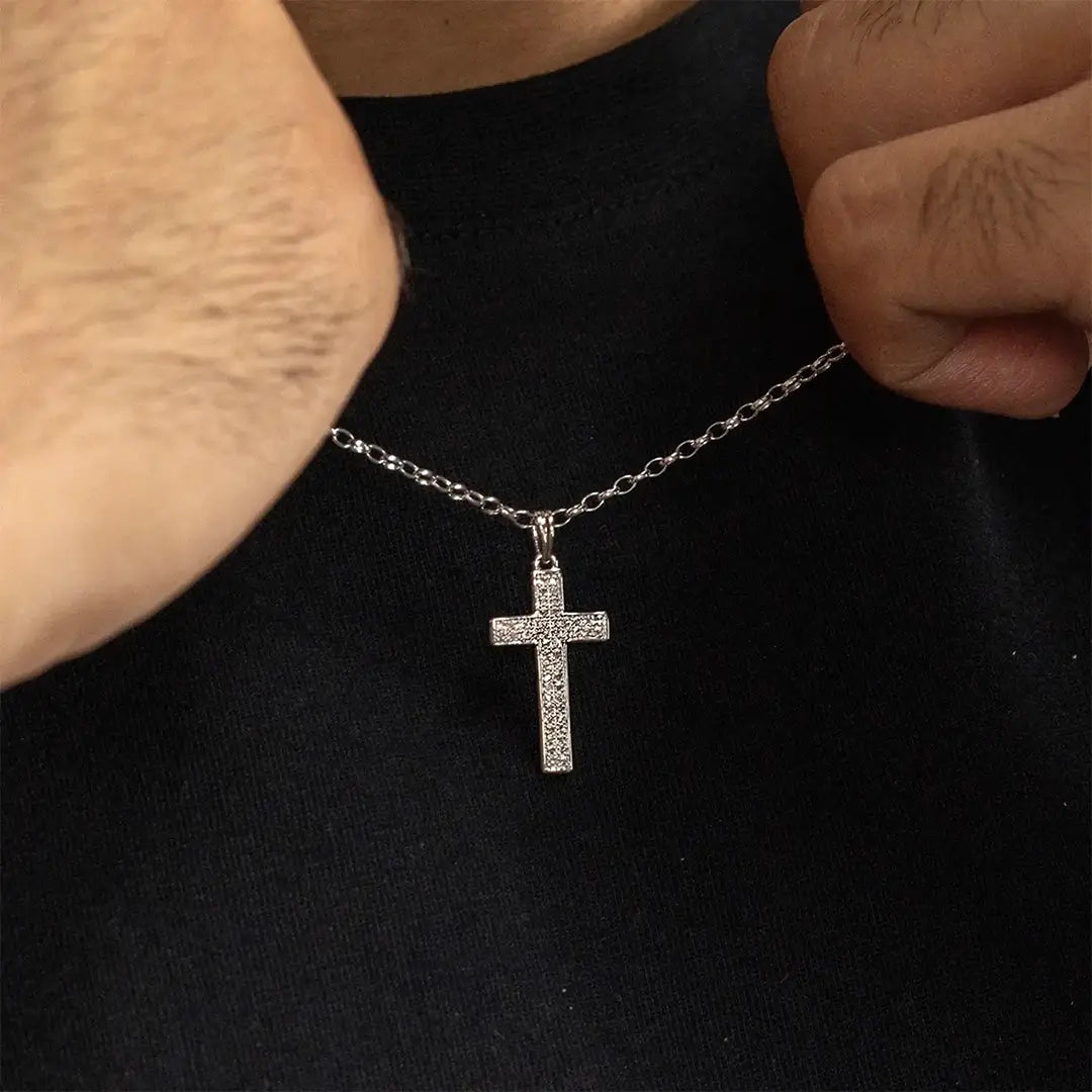 Close-up of white gold diamond cross pendant necklace held on chain, showcasing pavé diamond detail