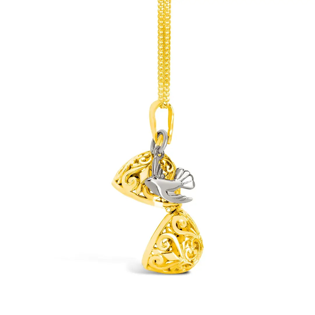 Side view of a gold filigree locket opened to show internal compartment and hinge detail