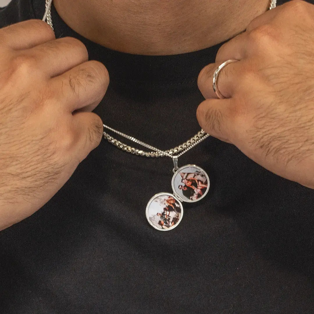 Close-up of a person holding an open silver locket necklace showing two personalised photo inserts inside