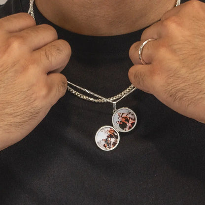 Close-up of a person holding an open silver locket necklace showing two personalised photo inserts inside