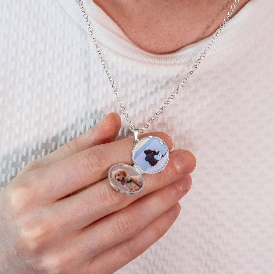Close-up of a sterling silver locket held in hand, opened to show two fitted personalised photos inside