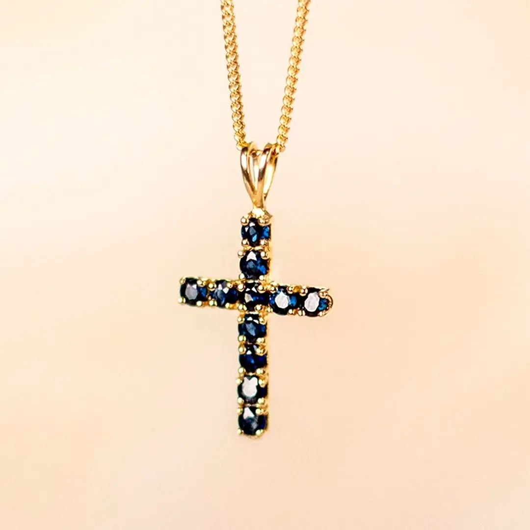 Gold cross pendant set with natural blue sapphires, fine chain luxury jewellery detail