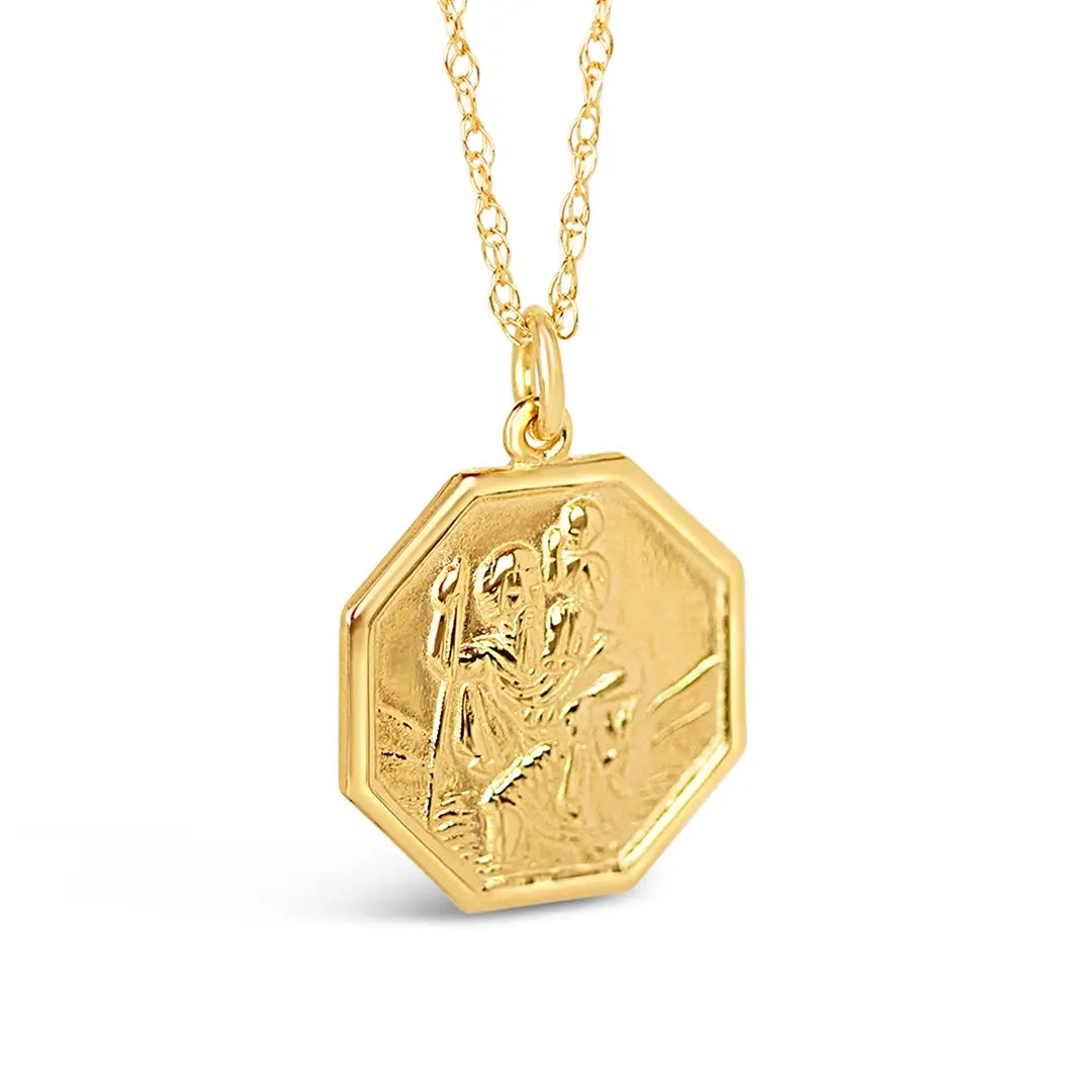 Close-up side view of gold hexagon St Christopher pendant showing polished edges and engraved detail