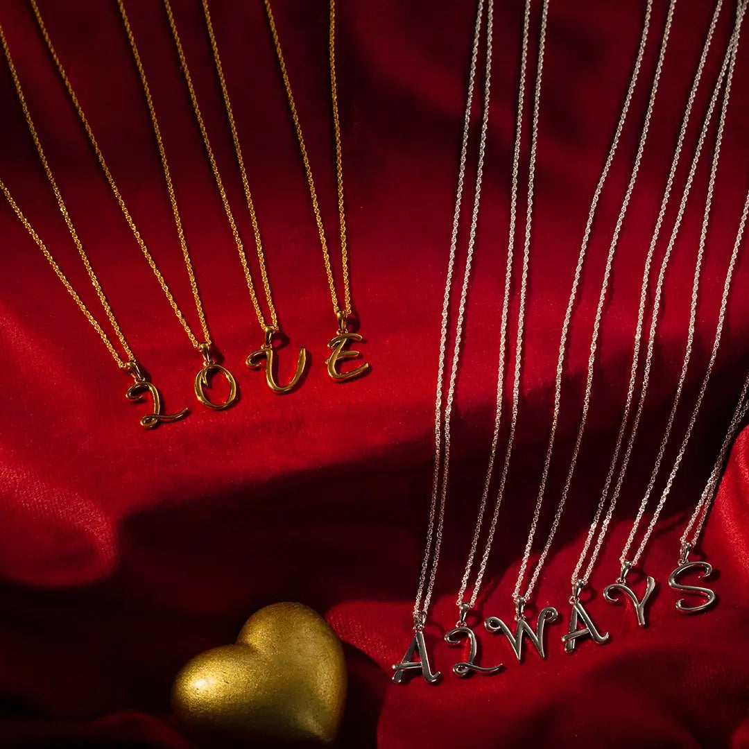Solid gold and sterling silver initial pendant necklaces spelling LOVE and ALWAYS on fine chains, personalised letter jewellery on red satin with gold heart