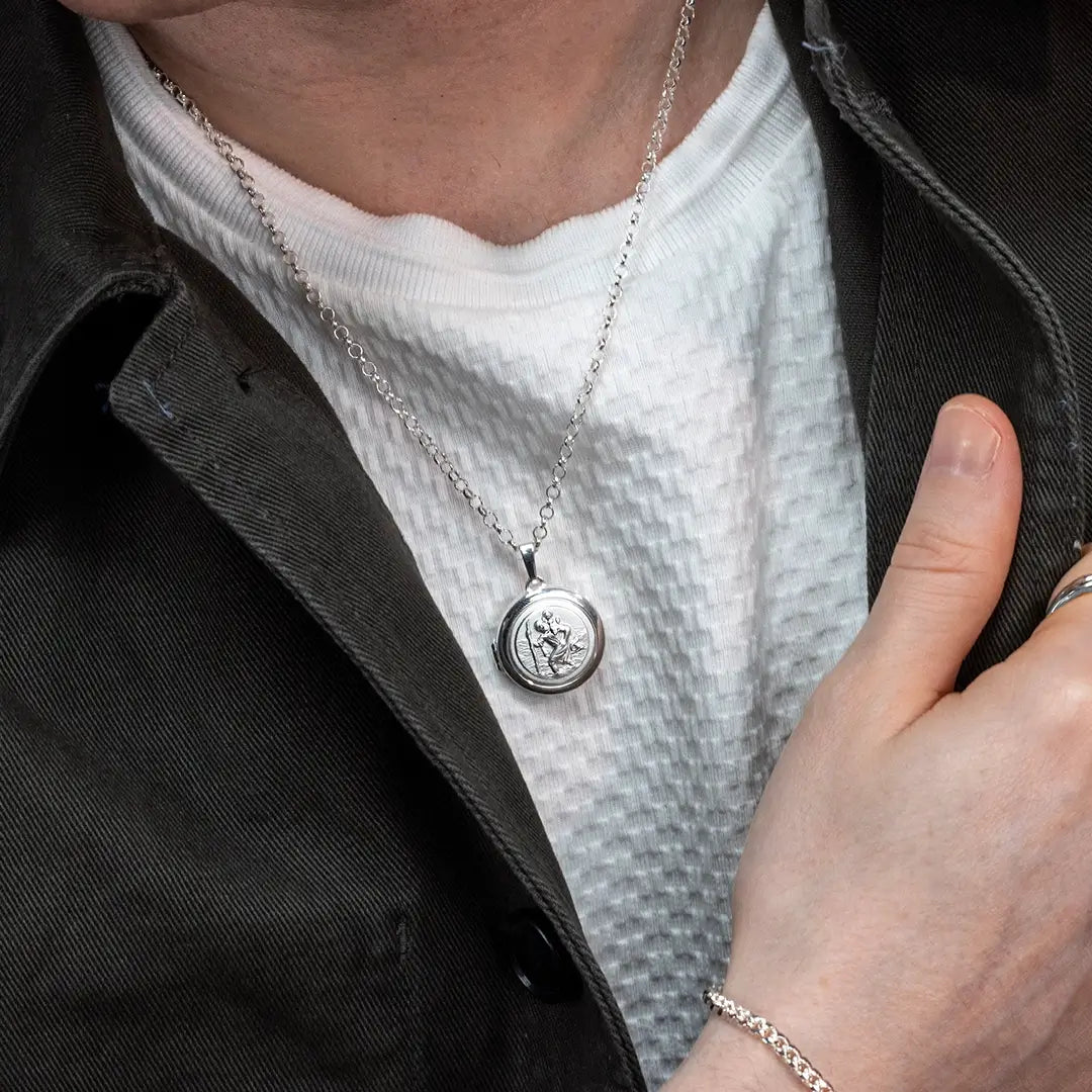 Mid-shot of a person wearing a sterling silver St Christopher locket necklace with casual styling