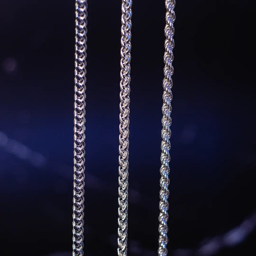 Three sterling silver chain styles displayed vertically including curb, spiga and rope chains on dark background