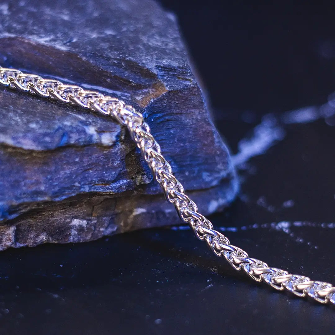 Sterling silver spiga chain bracelet styled on stone, textured jewellery detail. By Lily Blanche 