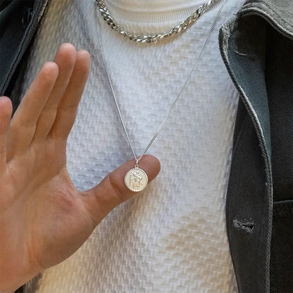 Man holding sterling silver St Christopher necklace, symbolic travel protection pendant close-up