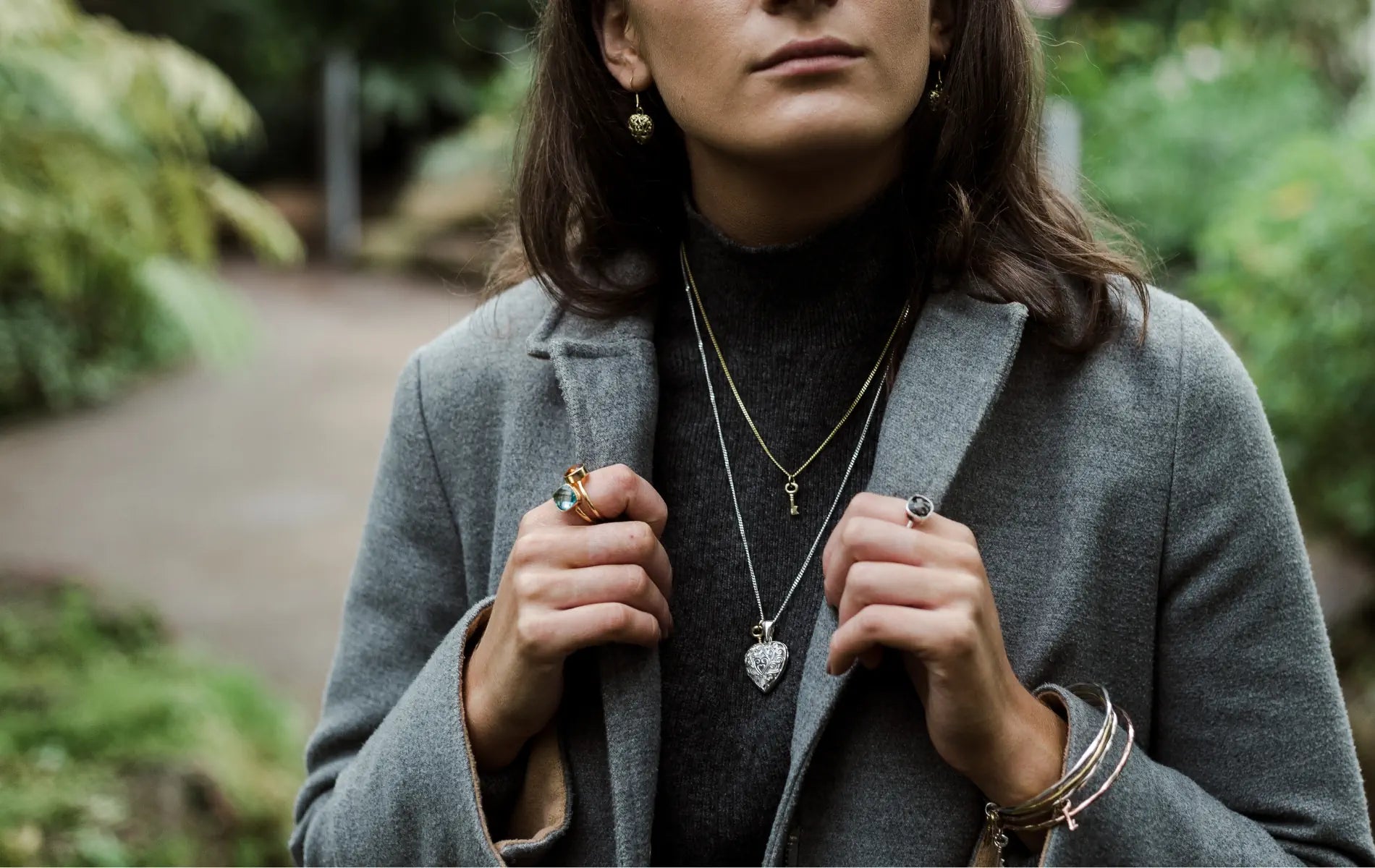Woman wearing a gray coat with jewellery outdoors
