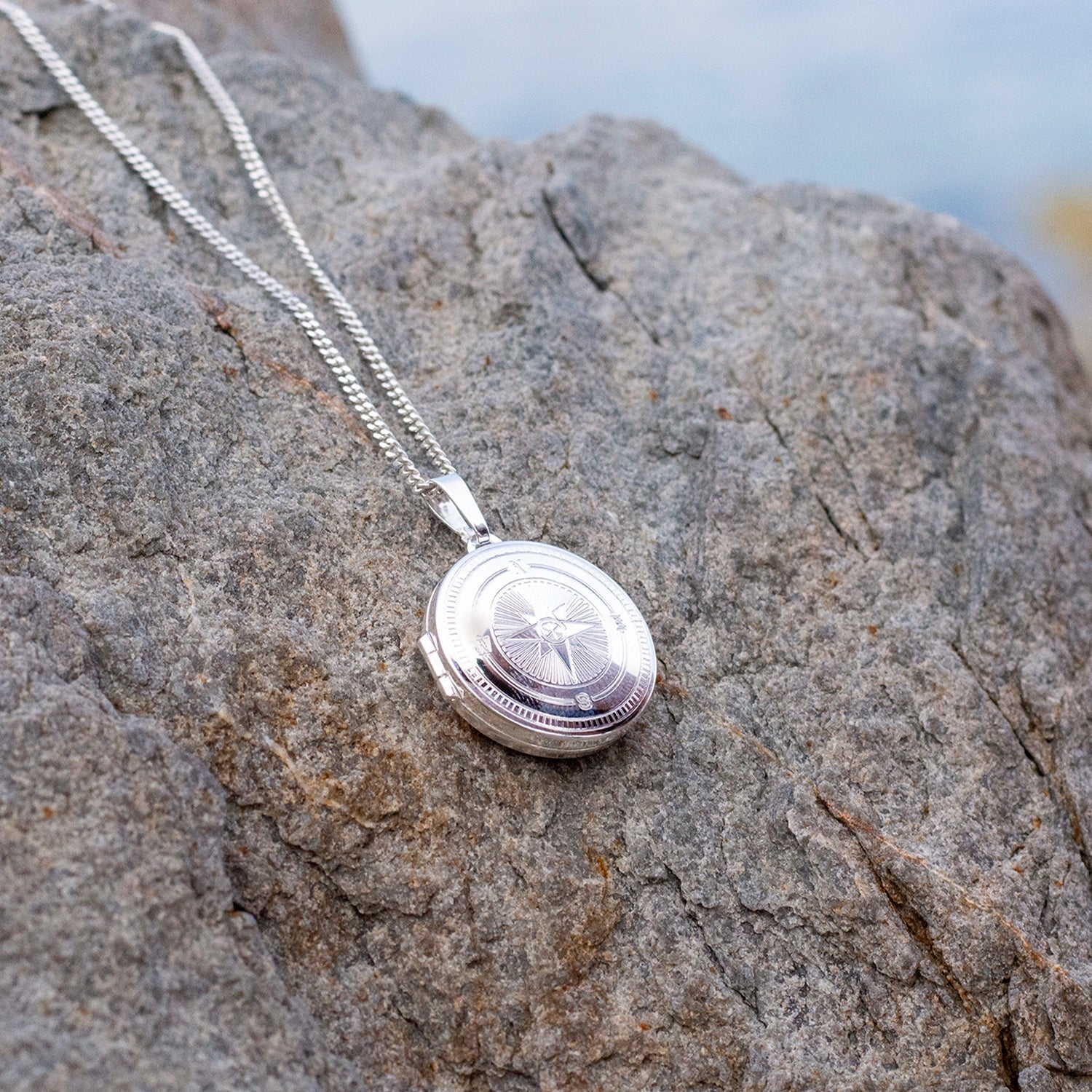 Silver locket necklace on a textured stone surface