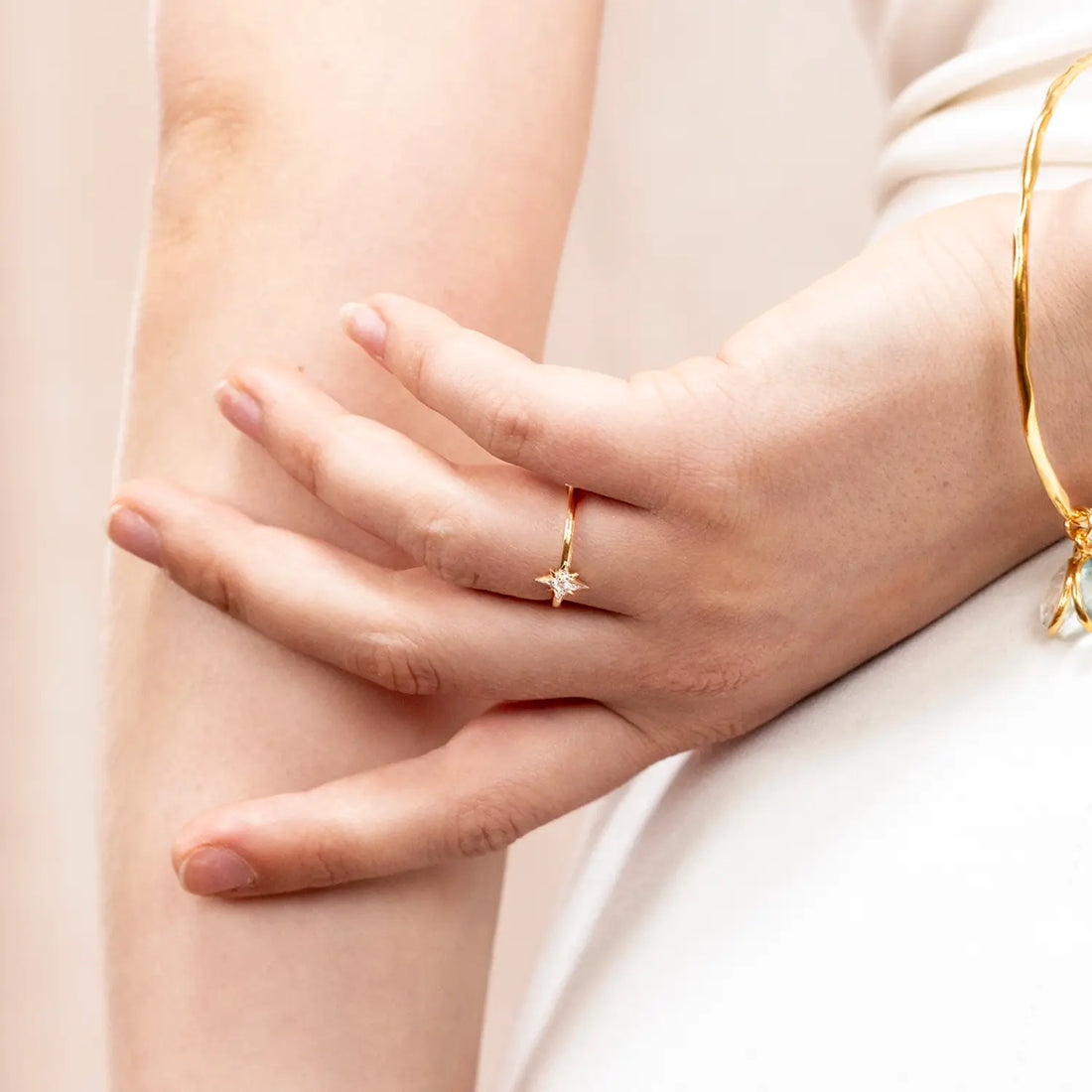 Woman's hand wearing a gold ring with a star design.