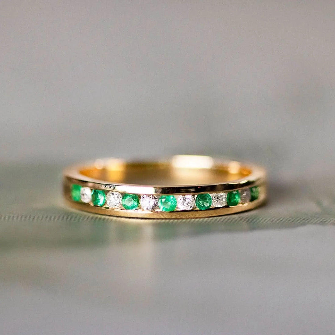 Gold eternity ring with channel-set emerald and diamond gemstones