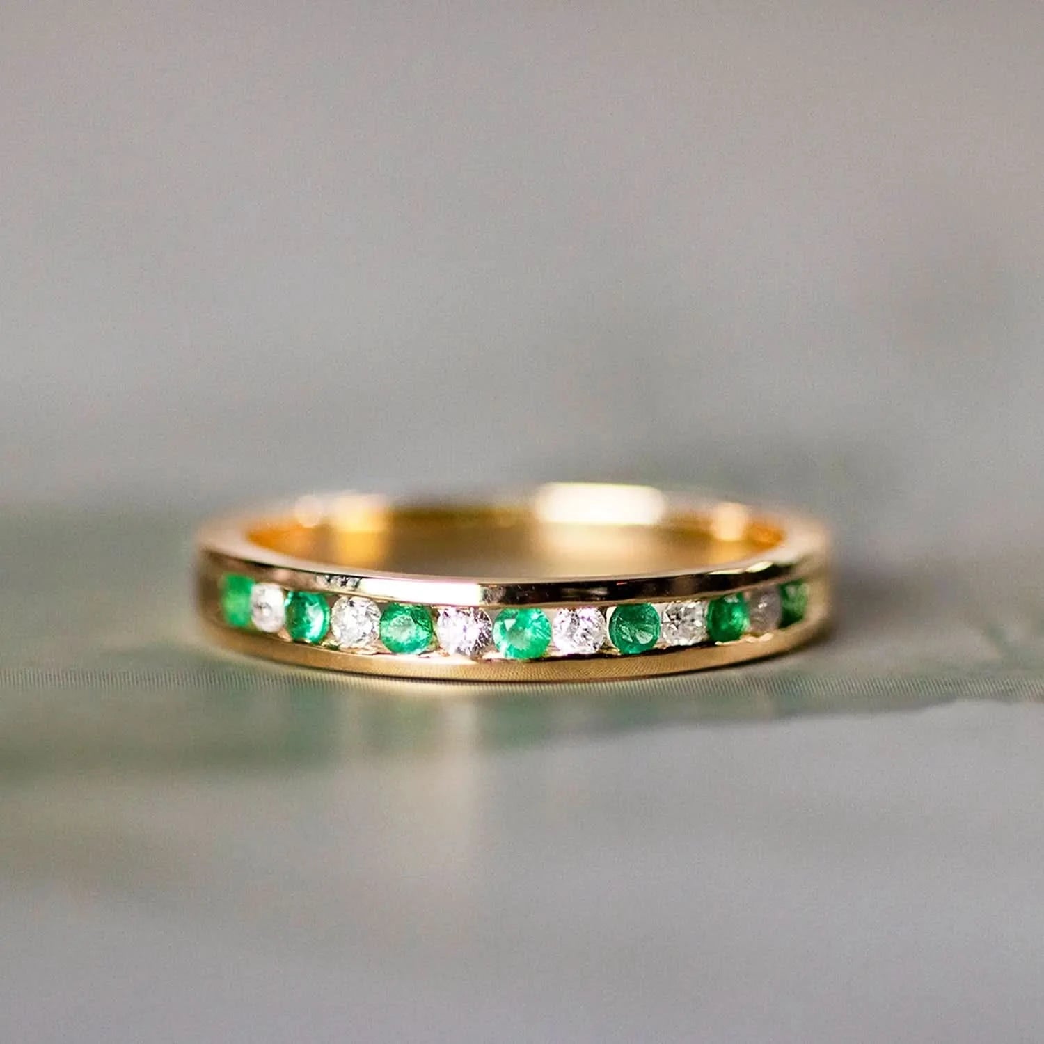 Gold eternity ring with channel-set emerald and diamond gemstones