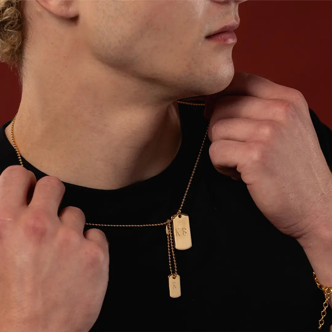 Close-up of engraved men’s double gold vermeil dog tag necklace showing K.B. and R initials on the two tags