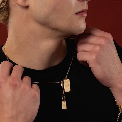 Close-up of engraved men’s double gold vermeil dog tag necklace showing K.B. and R initials on the two tags
