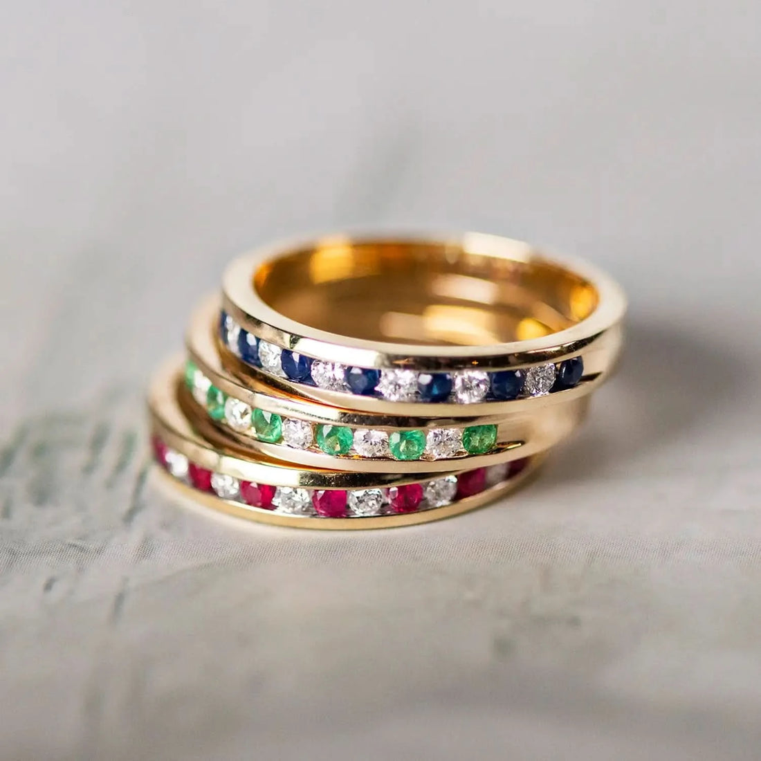 stack of gemstone and diamond gold band rings, ruby, emerald and sapphire