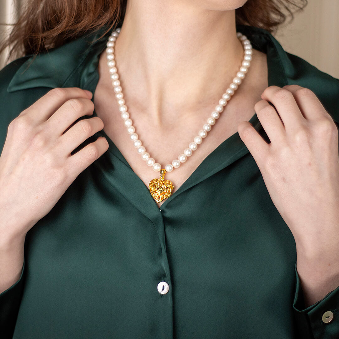 model wearing green shirt and white pearl necklace with gold filigree heart locket 